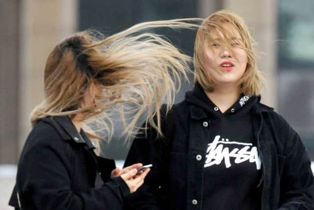 The hair of two young girls is caught in a gust of wind