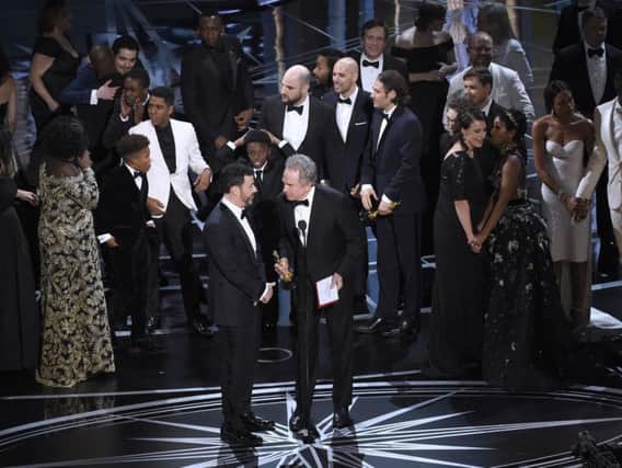 Host Jimmy Kimmel, left, and presenter Warren Beatty discuss the results of best picture as the casts of "La La Land" and "Moonlight," winner of best picture, react on stage at the Oscars.