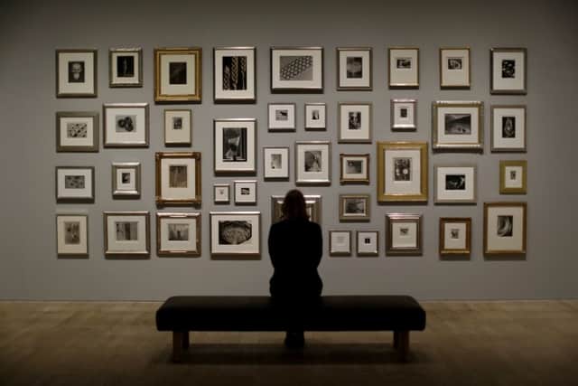 A Tate member of staff poses in front of a wall of photographs at the press view of "The Radical Eye: Modernist Photography from the Sir Elton John Collection" exhibition at the Tate Modern gallery in London.