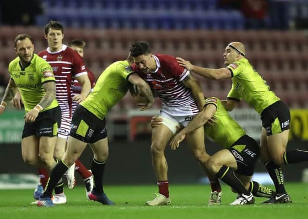 Wigan Warriors' Anthony Gelling is tackled by Hull FC's Marc Sneyd (left)  Mark Minichiello and Danny Houghton (right). Picture: Martin Rickett/PA.