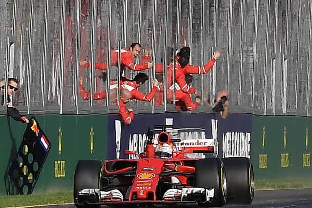 Ferrari driver Sebastian Vettel of Germany races past his celebrating team on the way to winning the Australian Formula One Grand Prix in Melbourne, Australia, Sunday, March 26, 2017. (AP Photo/Andy Brownbill)