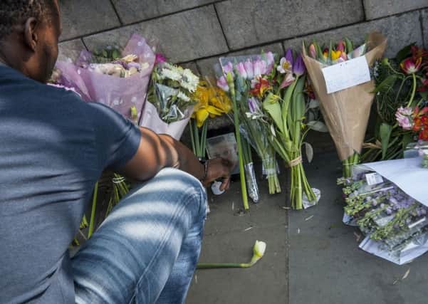 A man looks at a photograph of Pc Keith Palmer amongst floral tributes to the victims of the Westminster terrorist attack outside the Palace of Westminster, London.