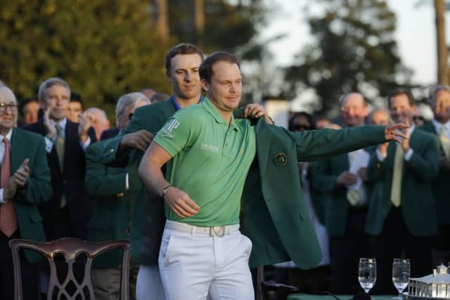 SUIT YOU SIR: 2015 champion Jordan Spieth, left, helps 2016 Masters champion Danny Willett put on his green jacket on. Picture: AP/Chris Carlson