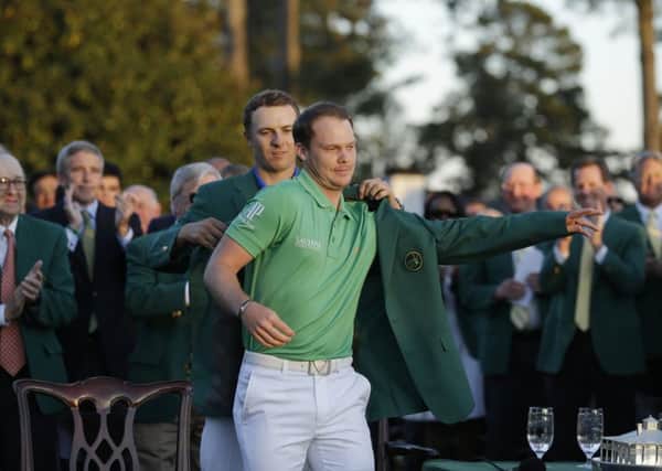 SUIT YOU SIR: 2015 champion Jordan Spieth, left, helps 2016 Masters champion Danny Willett put on his green jacket on. Picture: AP/Chris Carlson