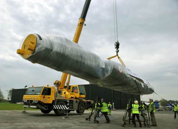 The body of the Mirage jet  is lifted by a crane  on to stands at the Yorkshire Air Museum at Elvington .
