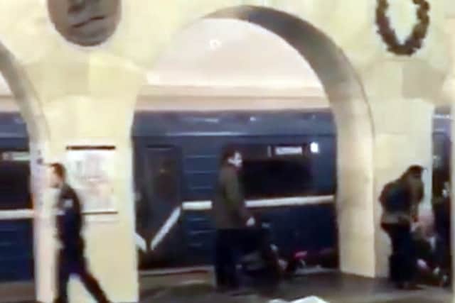 In this grab taken from AP video, Russian police officer, left, and people walk past the damaged train at the Tekhnologichesky Institut subway station in St.Petersburg