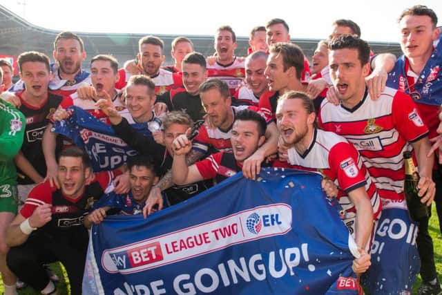 The Doncaster squad celebrate promotion on the pitch in front of the fans