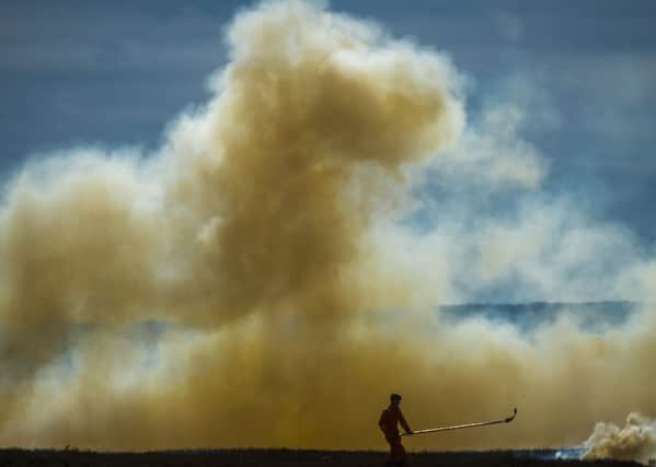 Fire beaters control the burning of heather on moorland near Dunford Bridge, in South Yorkshire.