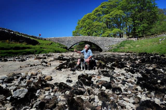 John Culley from Otley sits down with his dog Floss on the dried out River Wharfe at Yockenthwaite Bridge, Yockenthwaite near Buckden. Picture by Simon Hulme.