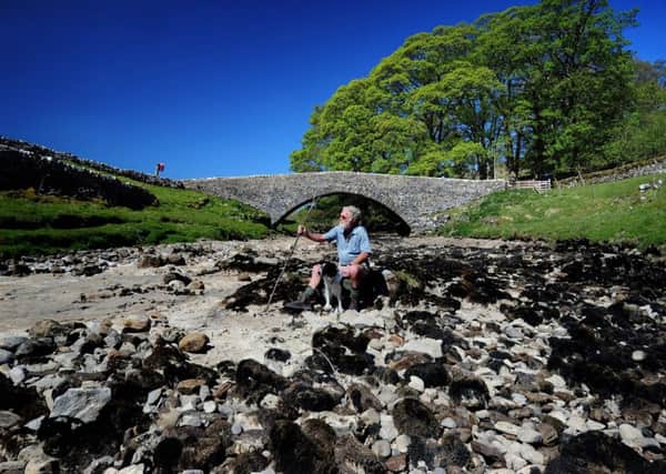John Culley from Otley sits down with his dog Floss on the dried out River Wharfe at Yockenthwaite Bridge, Yockenthwaite near Buckden. Picture by Simon Hulme.