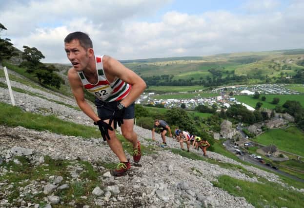 Competitors scramble up Kilnsey Crag.  Picture by Tony Johnson.