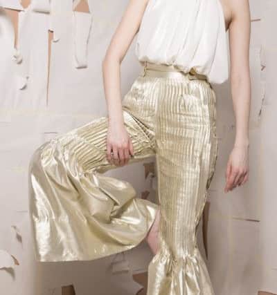 An outfit of drapey and flowing shapes, with cream halter neck top and metallic pleated flared trousers by Leeds College of Art Fashion graduate Priya Parmar.