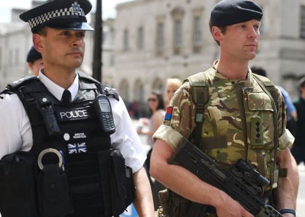 A member of the army joins police officers on Whitehall, London, after Scotland Yard announced armed troops will be deployed to guard "key locations" such as Buckingham Palace, Downing Street, the Palace of Westminster and embassies.