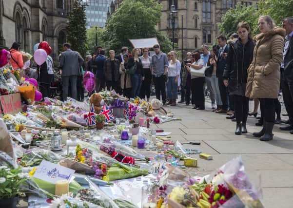 People look at flowers outside the Town Hall in Albert Square, Manchester. PIC: PA