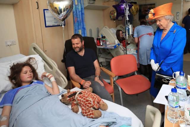 Queen Elizabeth II speaks to Evie Mills, 14, from Harrogate, and her dad, Craig, during a visit to the Royal Manchester Children's Hospital to meet victims of the terror attack in the city earlier this week and to thank members of staff who treated them. PA