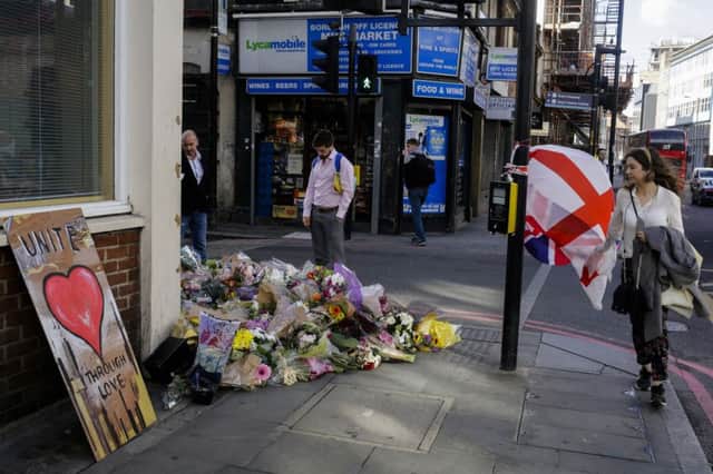 People pass flowers commemorate the victims of Saturday's attack at a street corner of the London Bridge area.
