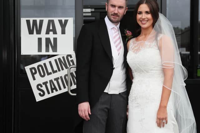 Alliance candidate for West Belfast Sorcha Eastwood casts her vote in the 2017 General Election, with her husband, Dale Shirlow, at a polling station in Lisburn, Northern Ireland, still wearing her wedding dress after they were married earlier in the day.