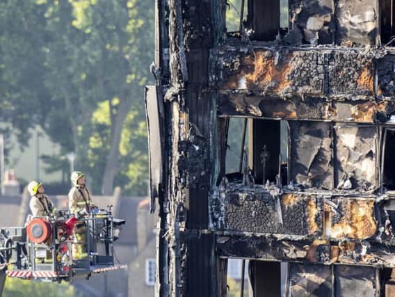 Fire service personnel survey the damage to Grenfell Tower in west London after a fire engulfed the 24-storey building on Wednesday morning. Picture: Rick Findler/PA Wire