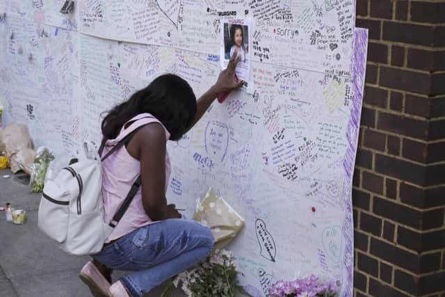A woman touches a missing poster for 12-year-old Jessica Urbano on a tribute wall after laying flowers on the side of Latymer Community Church next to the fire-gutted Grenfell Tower in London.