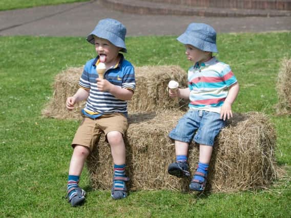 Brothers Oliver (left) and Benjamin Scott enjoy an ice cream at The Green in Heckmondwike, Yorskshire, as Britain basks in the hottest day of the year