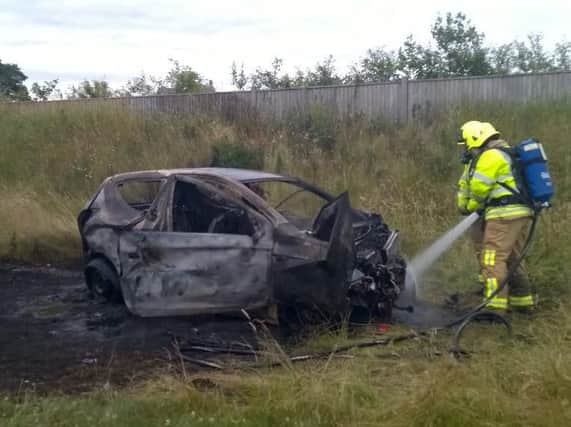 Firefighters continue to hose down the burned out car. Picture: Rob Horton, North Yorkshire Fire Service