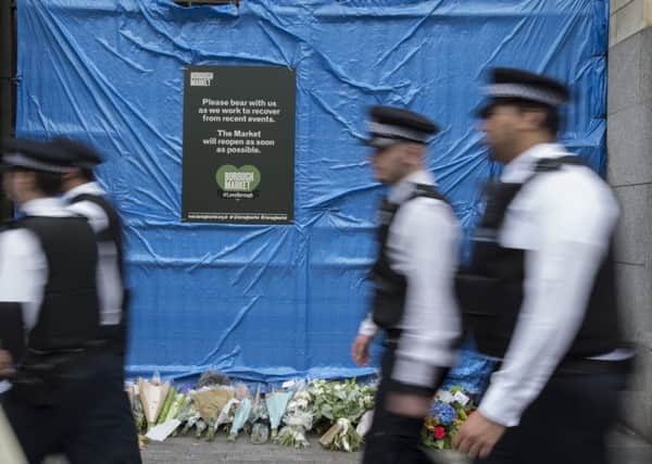Police officers walk past the scene of a recent terrorist atrocity at London Bridge.