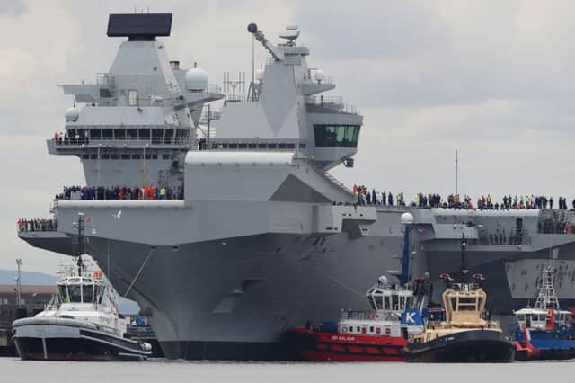 A police boat on the Firth of Forth as HMS Queen Elizabeth, one of two new aircraft carriers for the Royal Navy, begins to leave the Rosyth dockyard near Edinburgh to begin her sea worthiness trials