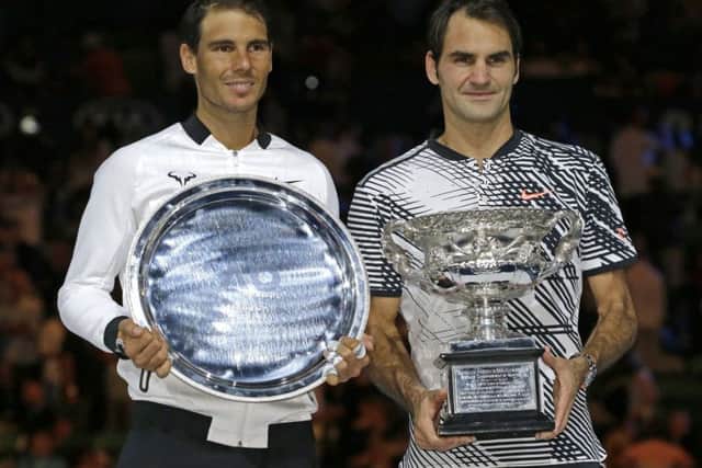 Switzerland's Roger Federer, right, and Spain's Rafael Nadal hold their trophies after Federer won their men's singles final at the Australian Open tennis championships in Melbourne