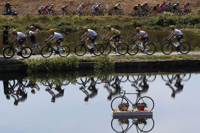 Britain's Geraint Thomas, wearing the overall leader's yellow jersey, and new overall leader Britain's Chris Froome, left of Thomas, are reflected in a pond as they ride in the pack during the fifth stage of the Tour de France. Picture: AP/Christophe Ena