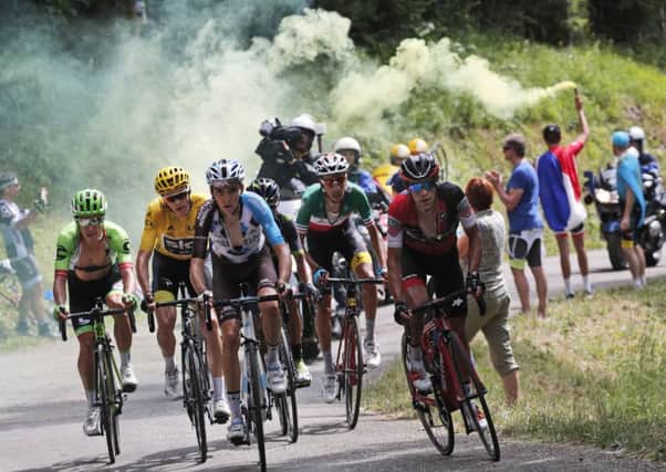 A spectator holds a flare as stage winner Colombia's Rigoberto Uran and Britain's Chris Froome, wearing the overall leader's yellow jersey, climb during the ninth stage of the Tour de France (Picture: Christophe Ena/AP).