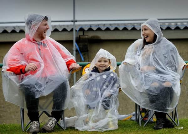 Robert and Kirsty Travis share a joke with their daughter Harper, aged four, in the pouring rain at the show. Picture by Simon Hulme.