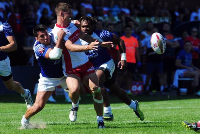 Hull KR player Jake Butler-Fleming releases the ball uinder pressure from the Toulouse defence.