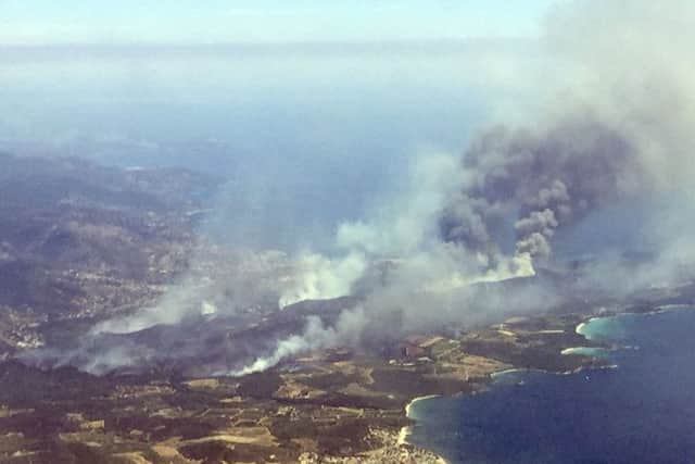 An aerial view shows plumes of smoke rising in the air from burning wildfires in the outskirts of Bormes-les-Mimosas, French Riviera, Wednesday, July 26, 2017. French authorities ordered the evacuation of up to 12,000 people around a picturesque hilltop town in the southern Cote d'Azur region as fires hopscotched around the Mediterranean coast for a third day Wednesday. (AP Photo/Nadine Achoui-Lesage)