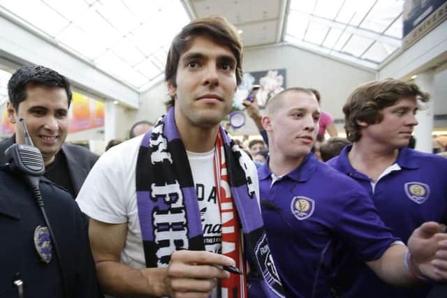 Brazilian soccer star Kaka, center, surrounded by security and police officers, makes his way through a crowd of fans at Orlando International Airport, Monday, June 30, 2014, in Orlando, Fla. Kaka was the first designated player to sign with the Orlando City Soccer Club ahead of the 2015 MLS season. (AP Photo/John Raoux)