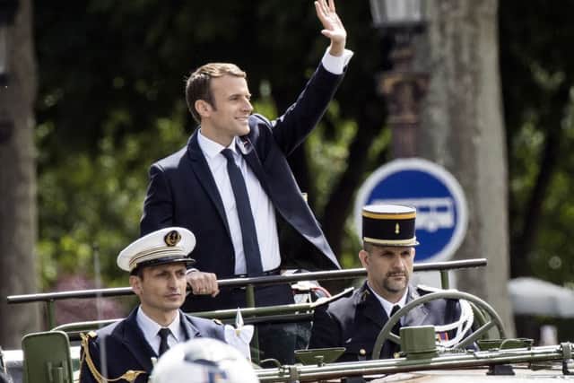 New French President Emmanuel Macron salutes the crowd from the command car on the Champs Elysees avenue