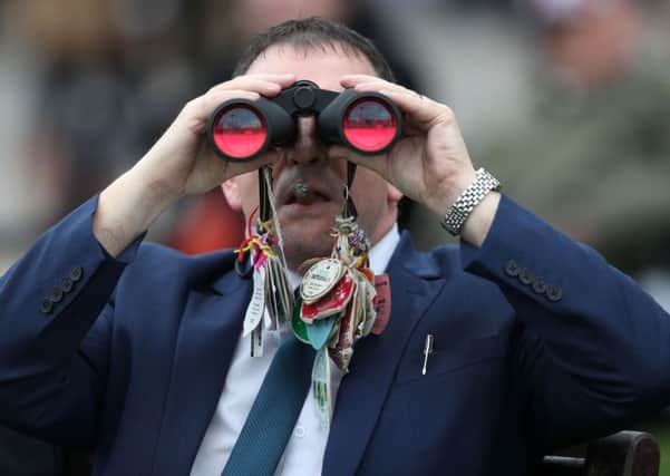 A racegoer looks through his binoculars