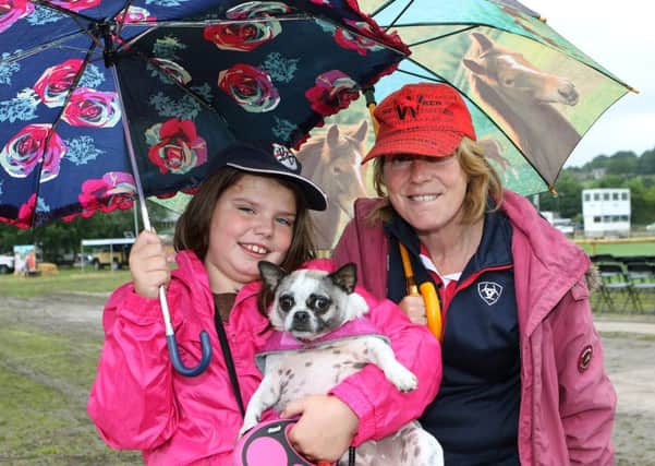 Umbrellas have been the order of the day at Bakewell Show. Pictured are show visitors Charlie May Parker and mum Vicky Clark with Bessie the dog.