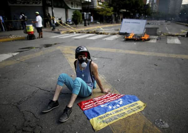 An anti-government demonstrator rests on the ground near a barricade in Caracas, Venezuela, Sunday, July 30, 2017. Venezuelans appear to be abstaining in massive numbers in a show of silent protest against a vote to select a constitutional assembly giving the government virtually unlimited powers. Across the capital on Sunday, dozens of polling places were empty or had a few dozens or hundreds of people outside, orders of magnitude less than the turnout in recent elections. (AP Photo/Ariana Cubillos)