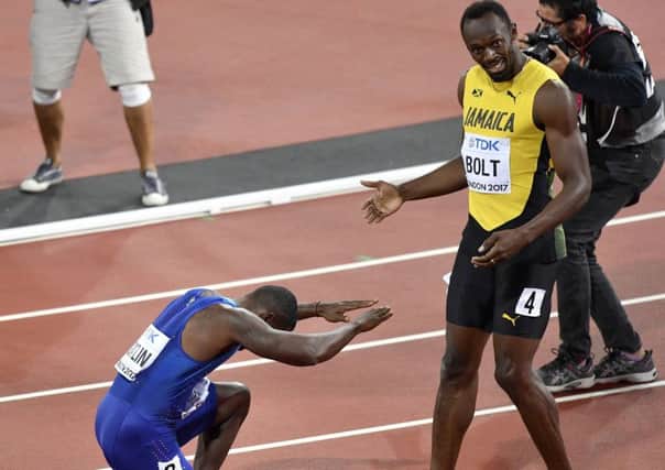 Justin Gatlin, left, bows as he celebrates his win in the Men's 100m final as third placed Jamaica's Usain Bolt watches. (AP).