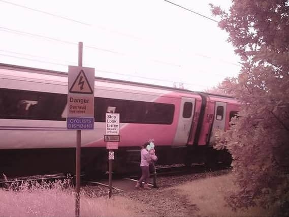 The youngsters were pictured just inches from a fast-moving train.
