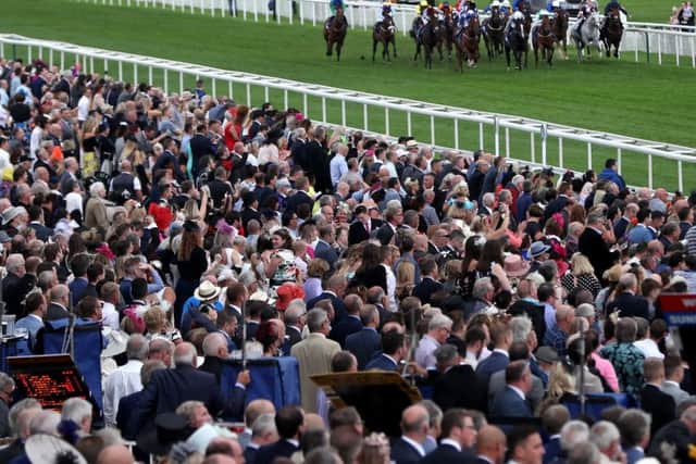 PACKED OUT: Race goers look on as Flaming Spear ridden by Robert Winston goes on to win The Clipper Logistics Stakes during Ladies Day at York's Ebor Festival. Picture: Simon Cooper/PA