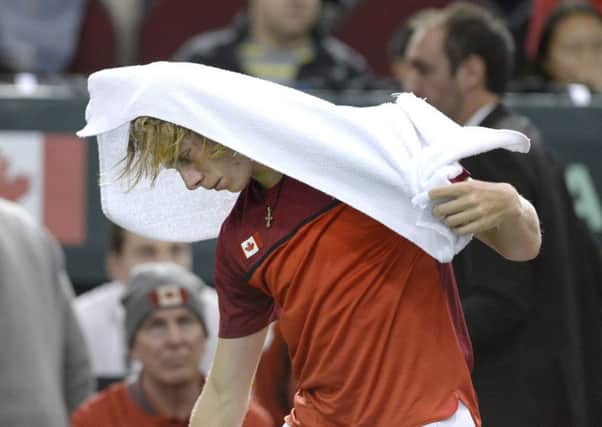Canada's Denis Shapovalov covers his head with a towel having been disqualified after accidentally hitting a ball into the face of umpire Arnaud Gabas in his Davis Cup match with Britain's Kyle Edmund (Picture: Justin Tang/The Canadian Press via AP).