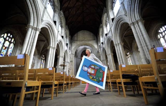 Elspeth Williams  from  the Great North Art Show carrying  a painting 'Prize Catch' by Adam King from Scarborough  across the aisle  in Ripon Catherdal.