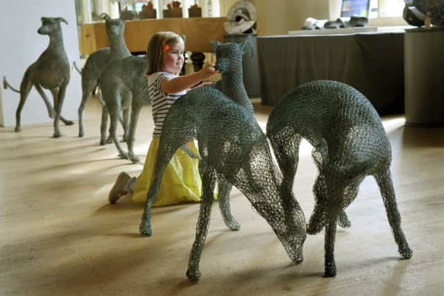 Scarlett Williams, 3, looking at  sculptures by Chris Moss made from chicken wire  at the Great North Art Show  in Ripon Catherdal.