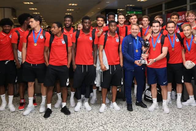 The England U20's squad and manager Paul Simpson pose with the World Cup after their arrival back at Birmingham Airport.