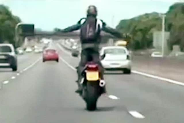 Wheelie stupid: The man stands up with his arms outstretched while on the bike on the motorway