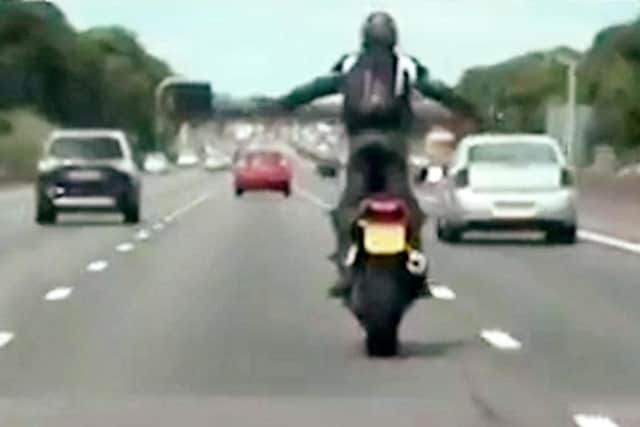 Wheelie stupid: The man stands up with his arms outstretched while on the bike on the motorway