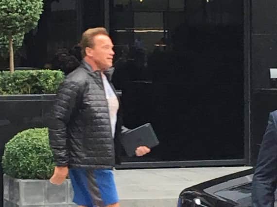 Arnold Schwarzenegger clutches an iPad as he walks to his Rolls Royce