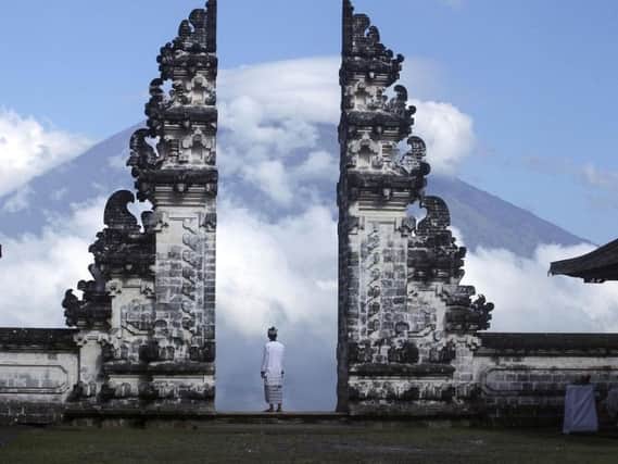 Balinese man watches Mount Agung volcano almost covered with clouds as he stands at a temple in Karangasem, Bali, Indonesia. Picture: AP Photo/Firdia Lisnawati.
