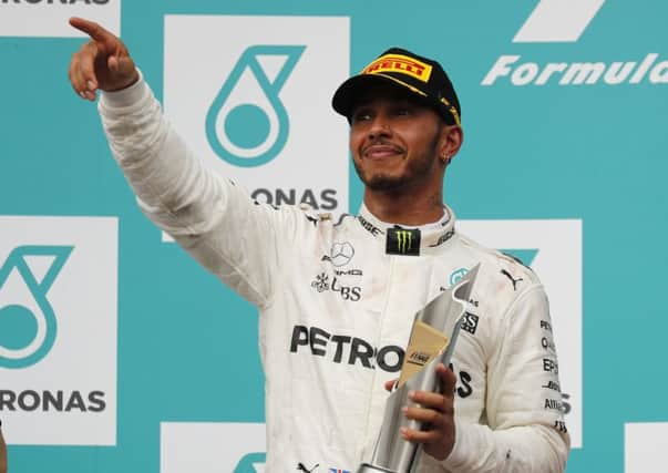 Britains Lewis Hamilton shows off his trophy after his second-place finish at the Malaysian Grand Prix behind Hollands Max Verstappen (Picture: Vincent Thioan/AP).
